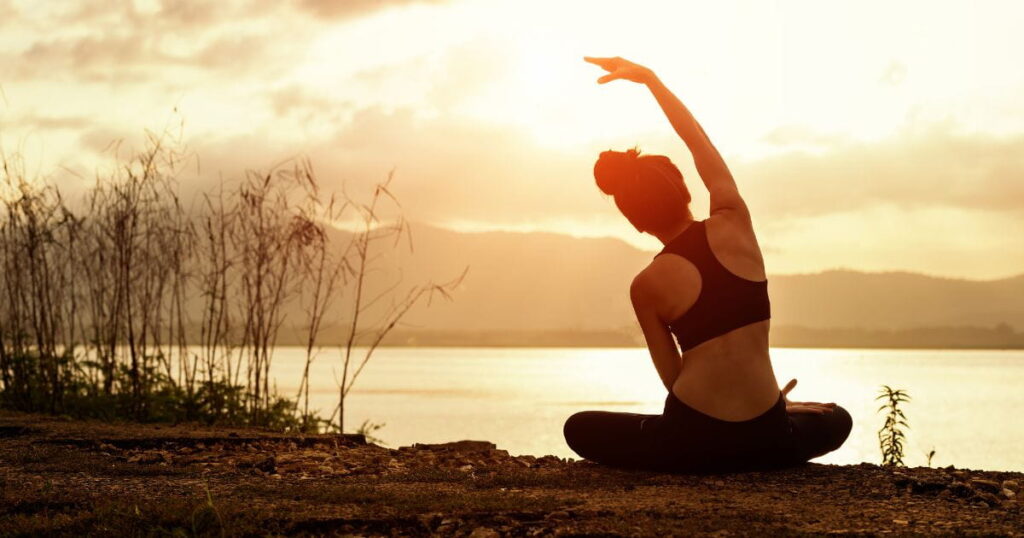 femme qui fait du yoga sur le bord d'un étang